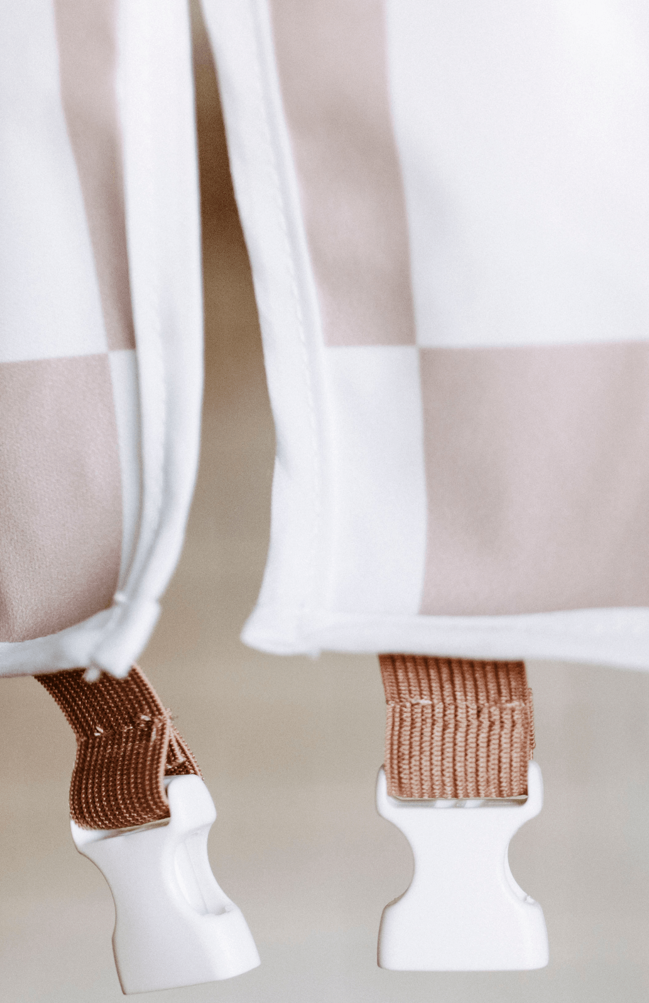 Close-up of the Bibvy bib's mauve pink adjustable buckle detail on a checkered print