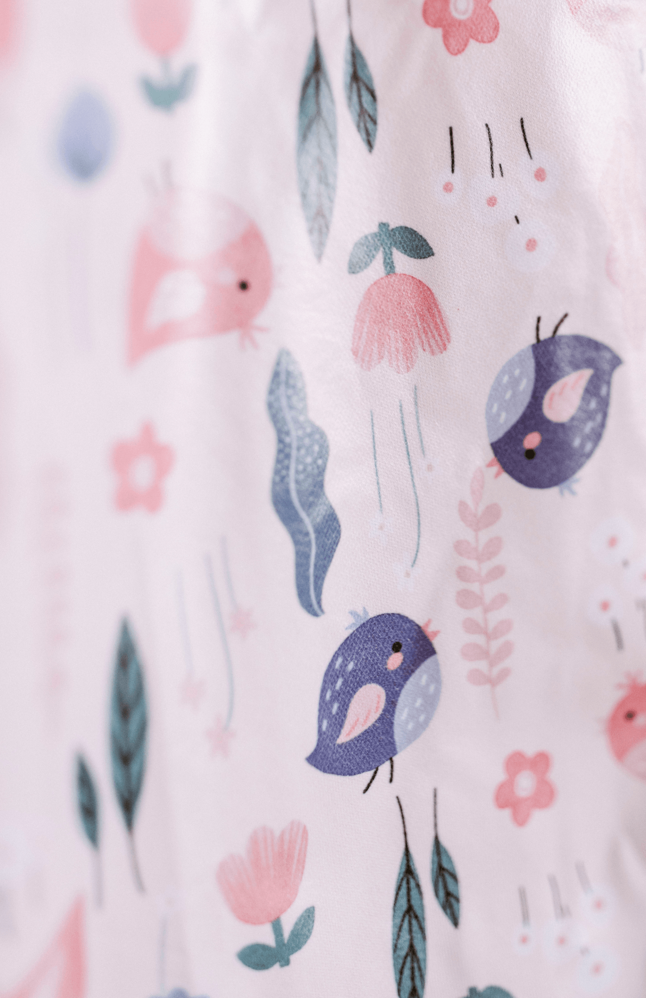 Close-up of the Bibvy 'Little Birdie' print featuring whimsical birds and floral patterns on a bib.